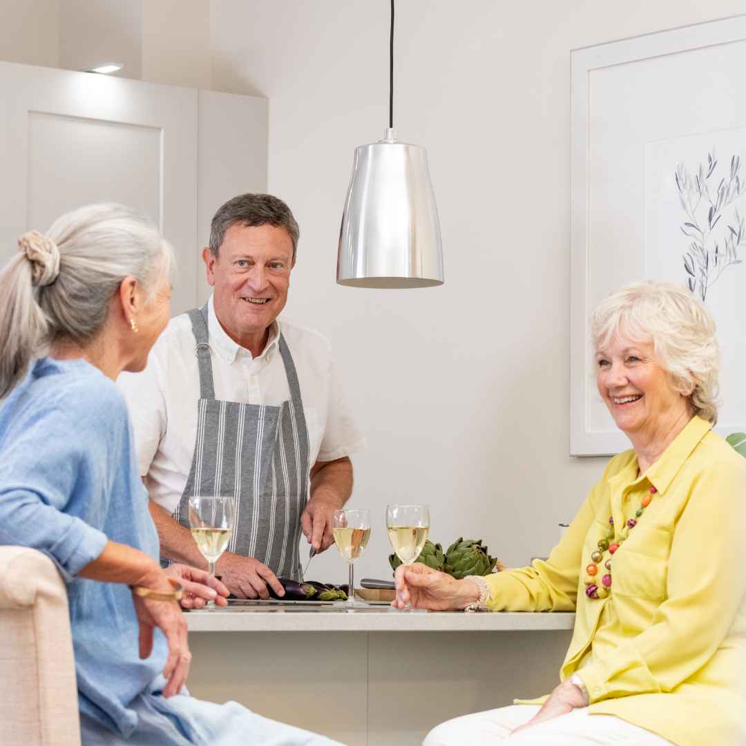 Three people with white wine in a kitchen