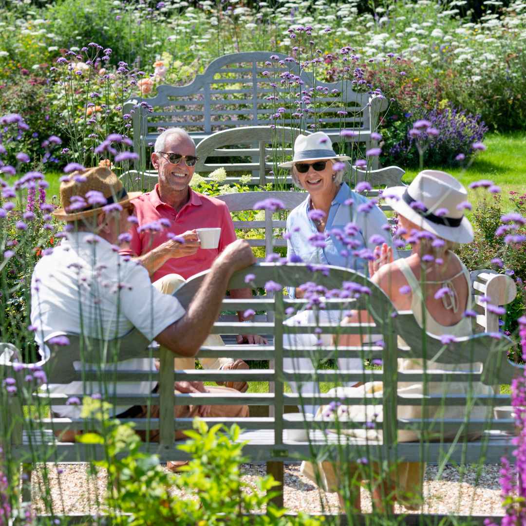 Four people sat on benches in a beautiful garden