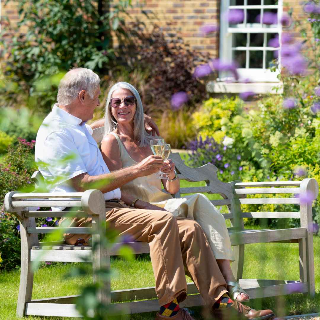 A couple sat on a bench outside in a garden
