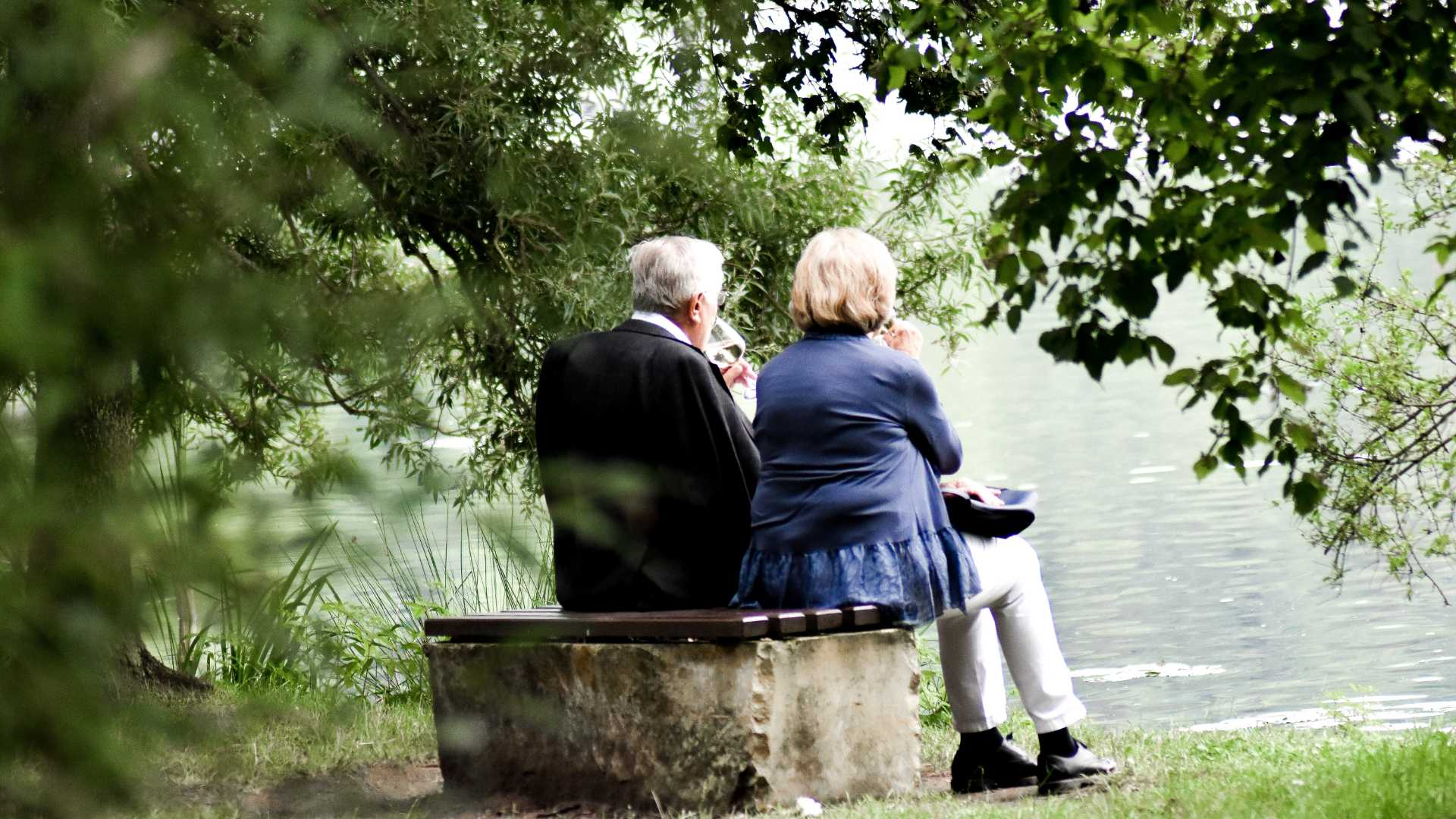A retired couple sitting on a bench by the water