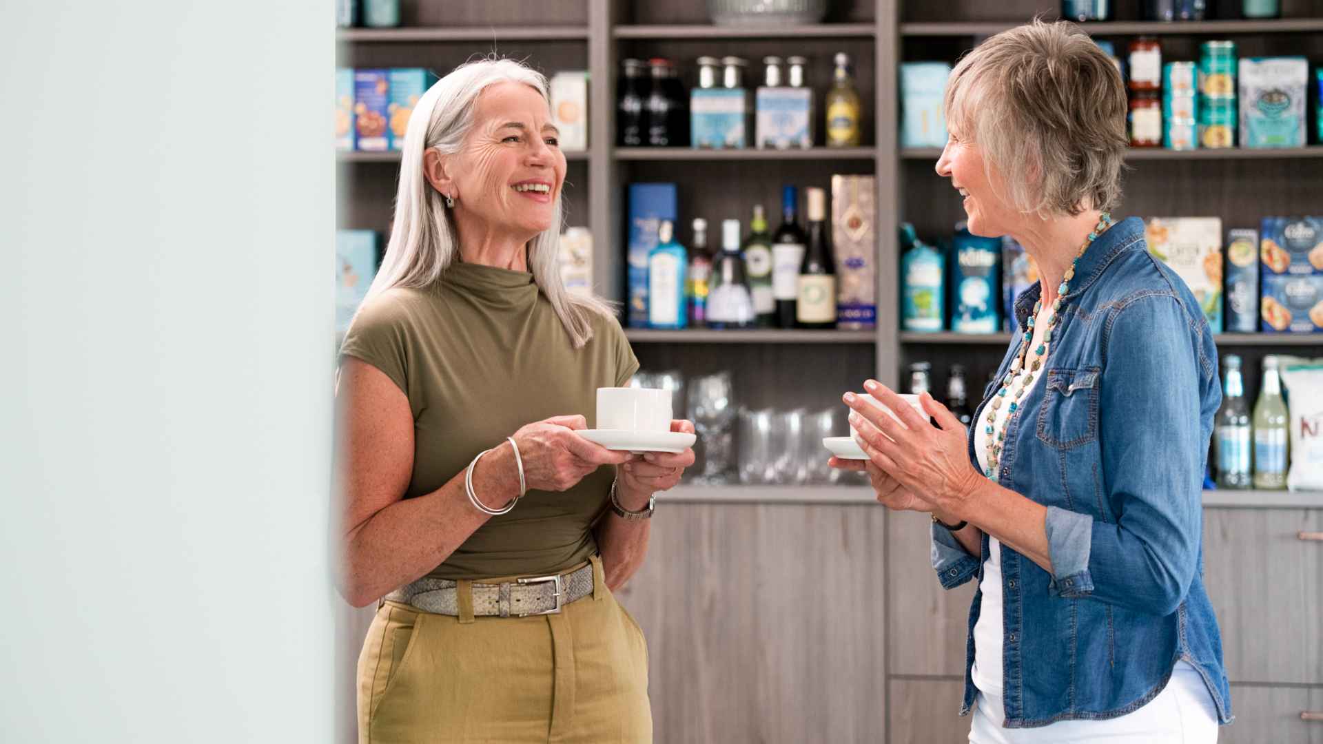 Two ladies speaking with coffee in hand