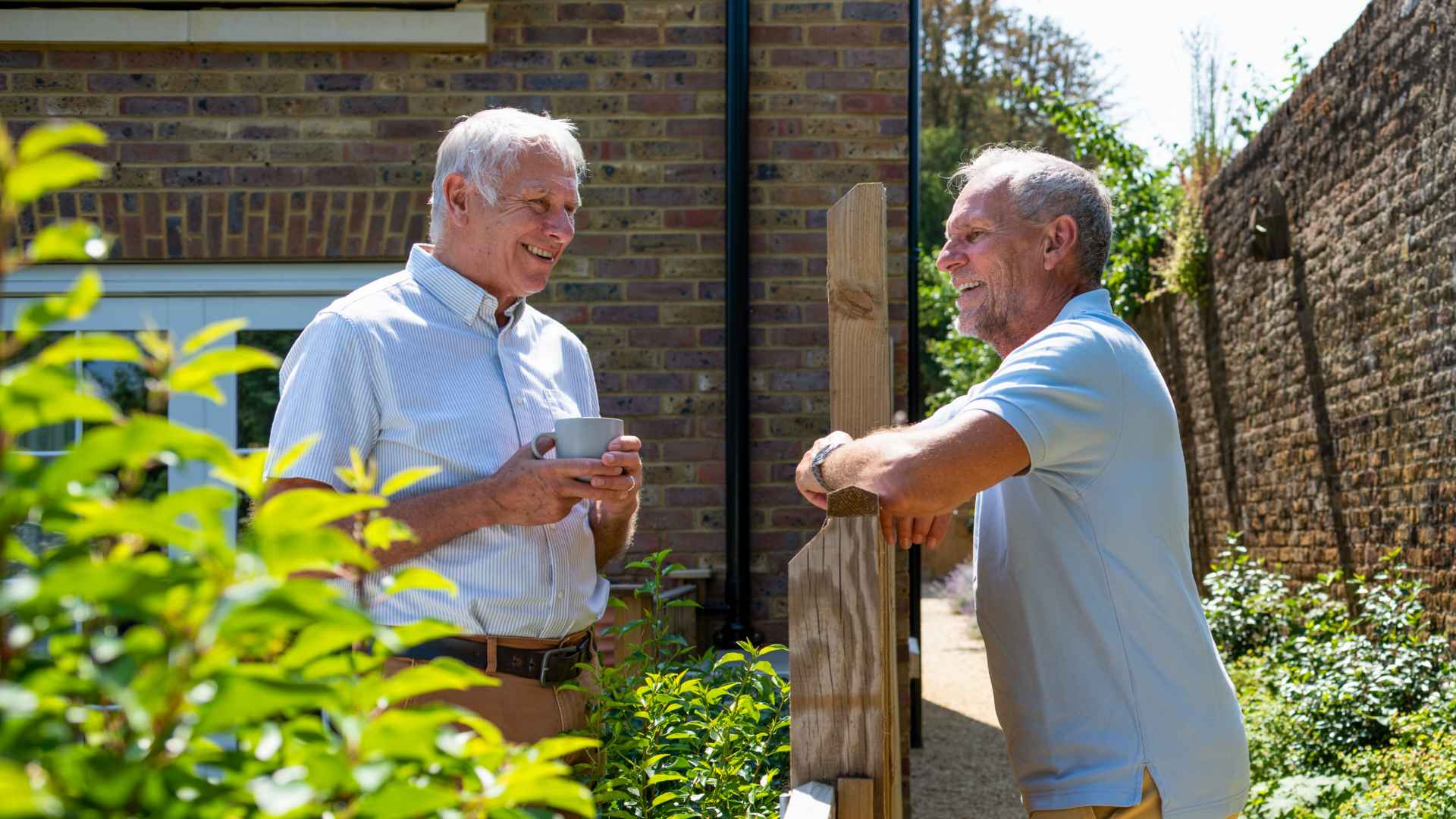 Two men speak to each other across a fence