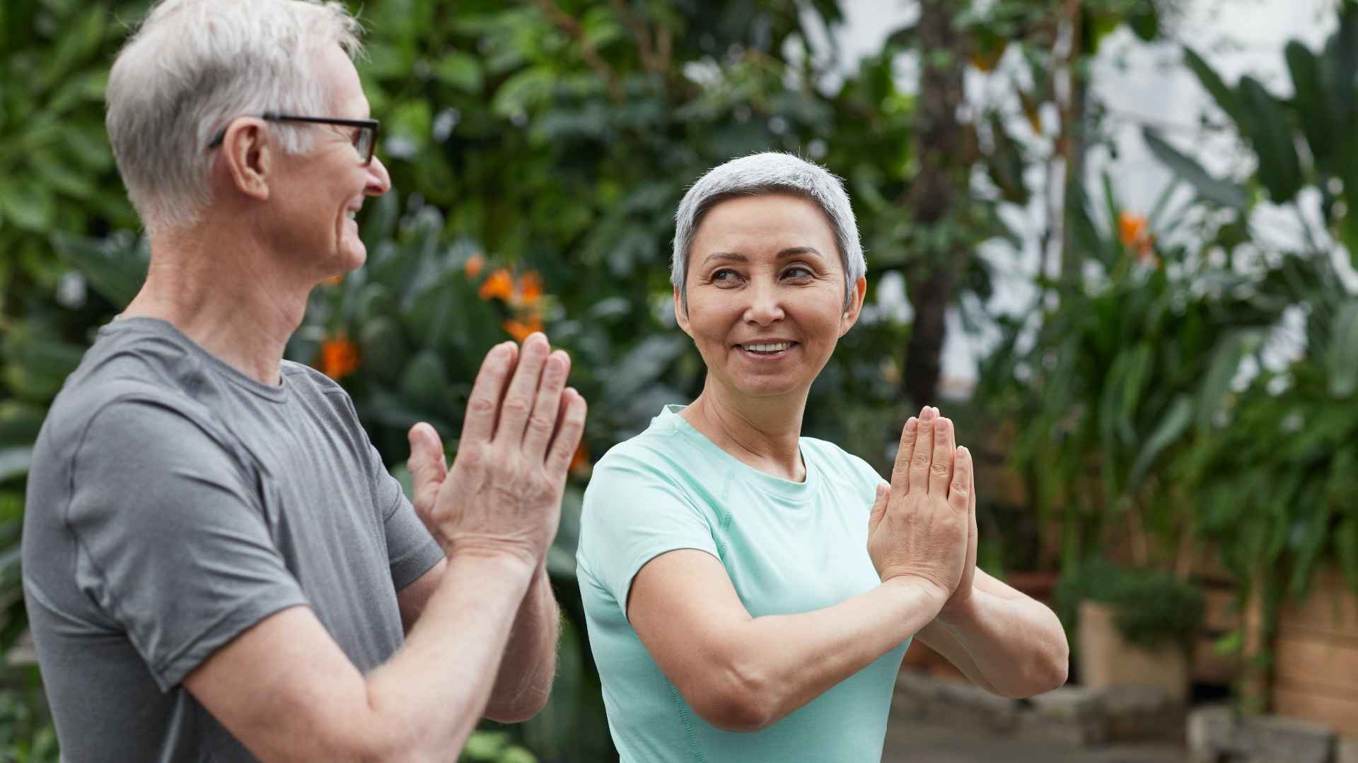 Two older people practising yoga together
