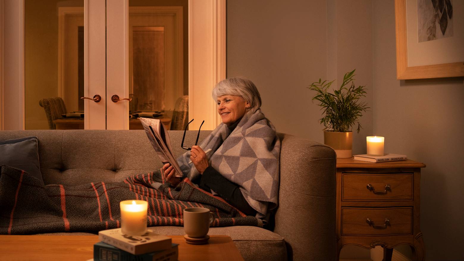 A photo of an older lady reading a newspaper in her drawing room