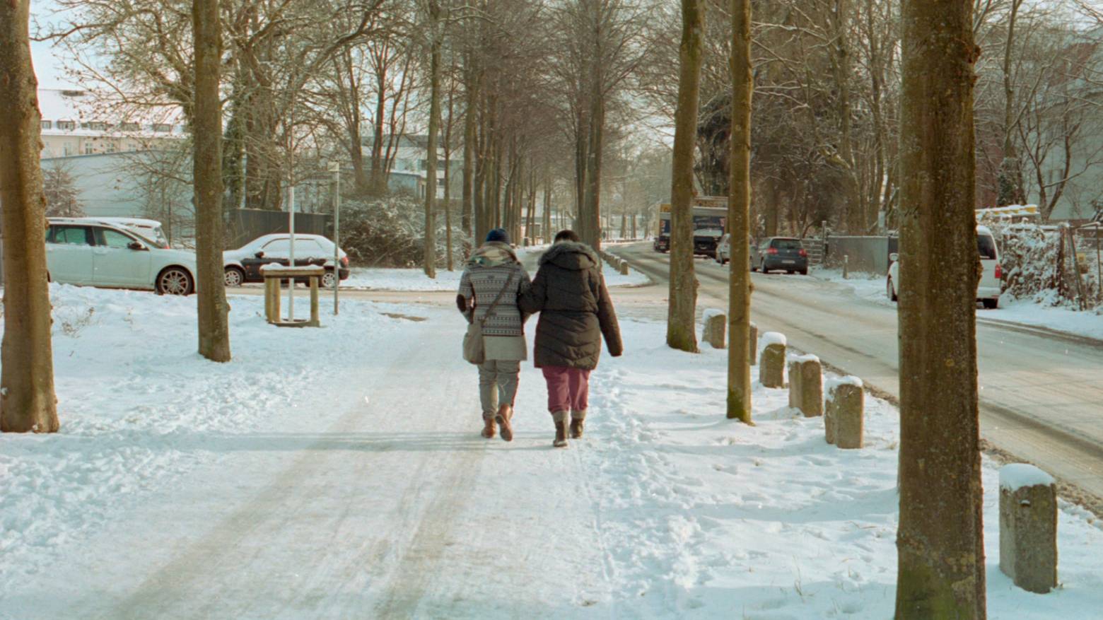 An elderly couple walking down a snowy street