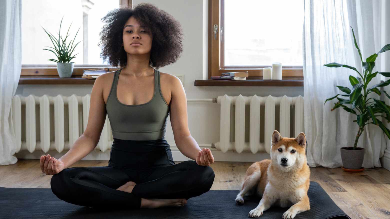 A woman and a dog on a yoga mat. 