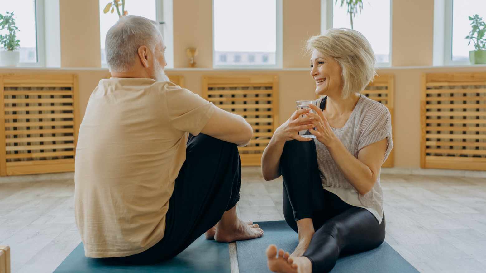 An elderly couple relaxing on yoga mats. 