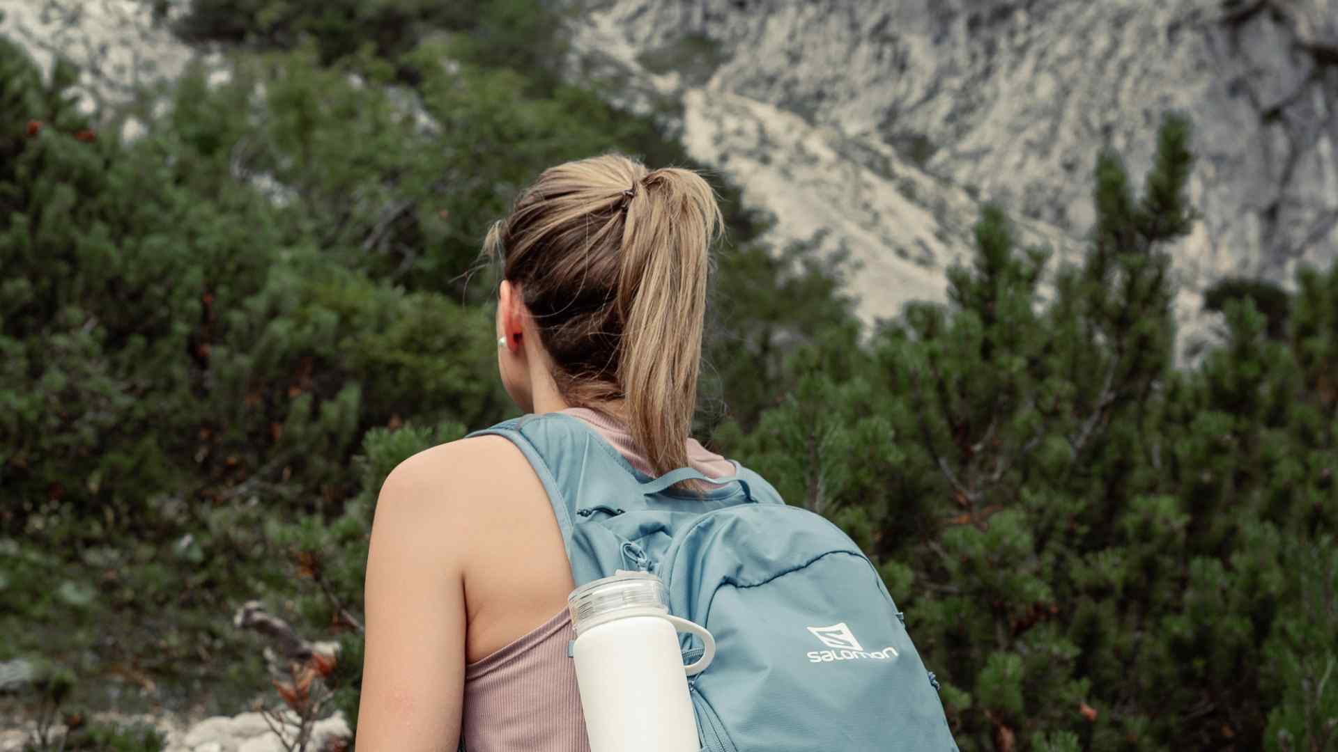 A blonde woman in sunglasses drinking water