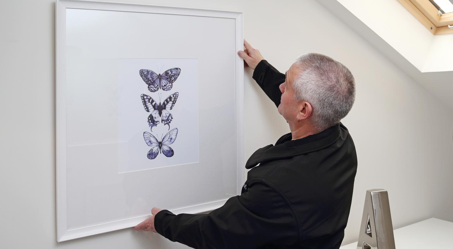 A Beechcroft handyman hanging up a frame