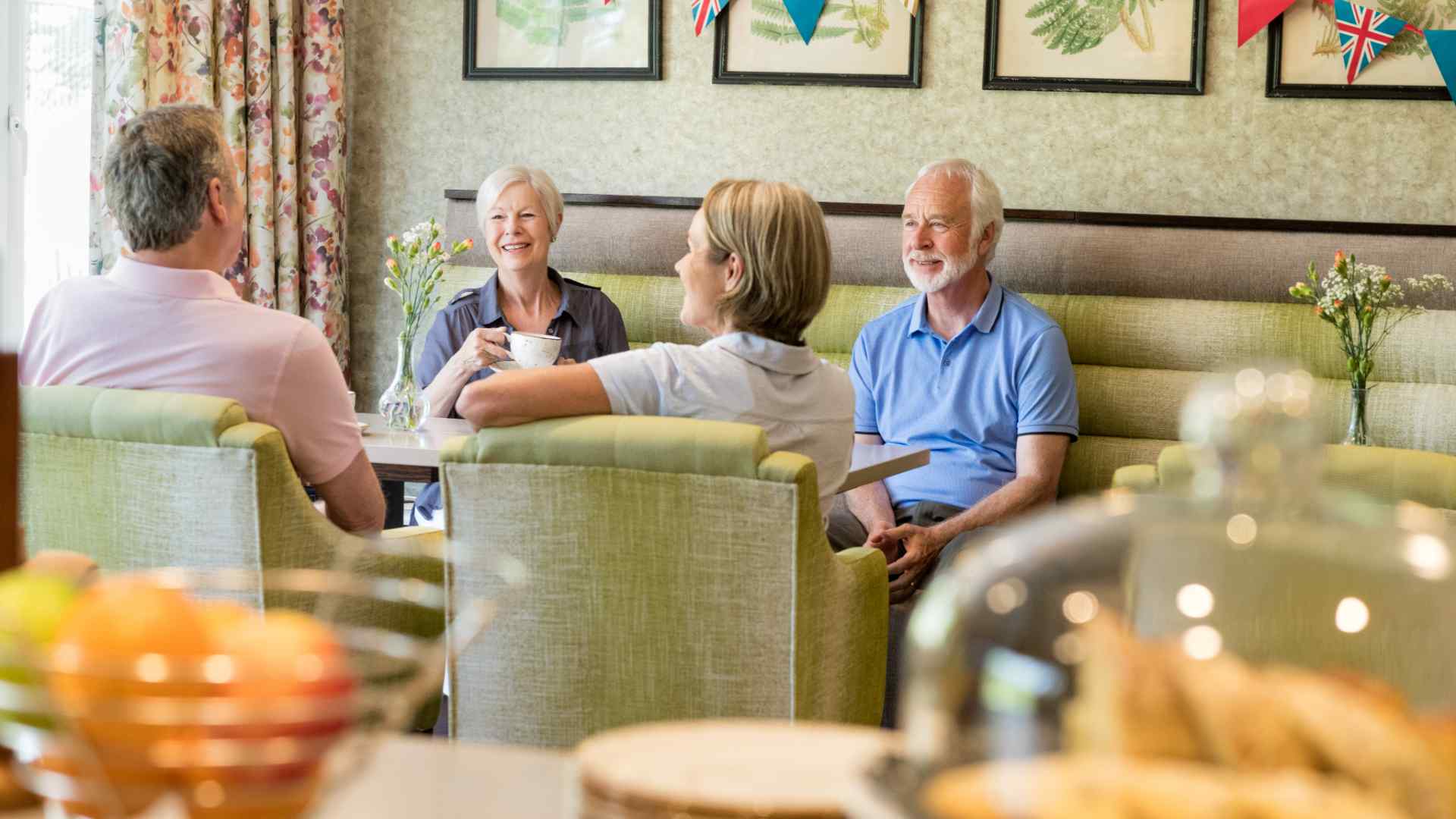 Four friends in a communal lounge of a retirement development enjoying a cup of coffee.