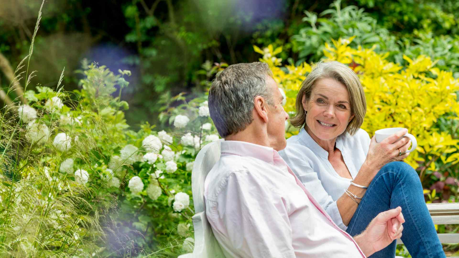 A man and a woman sitting on a bench in the garden.