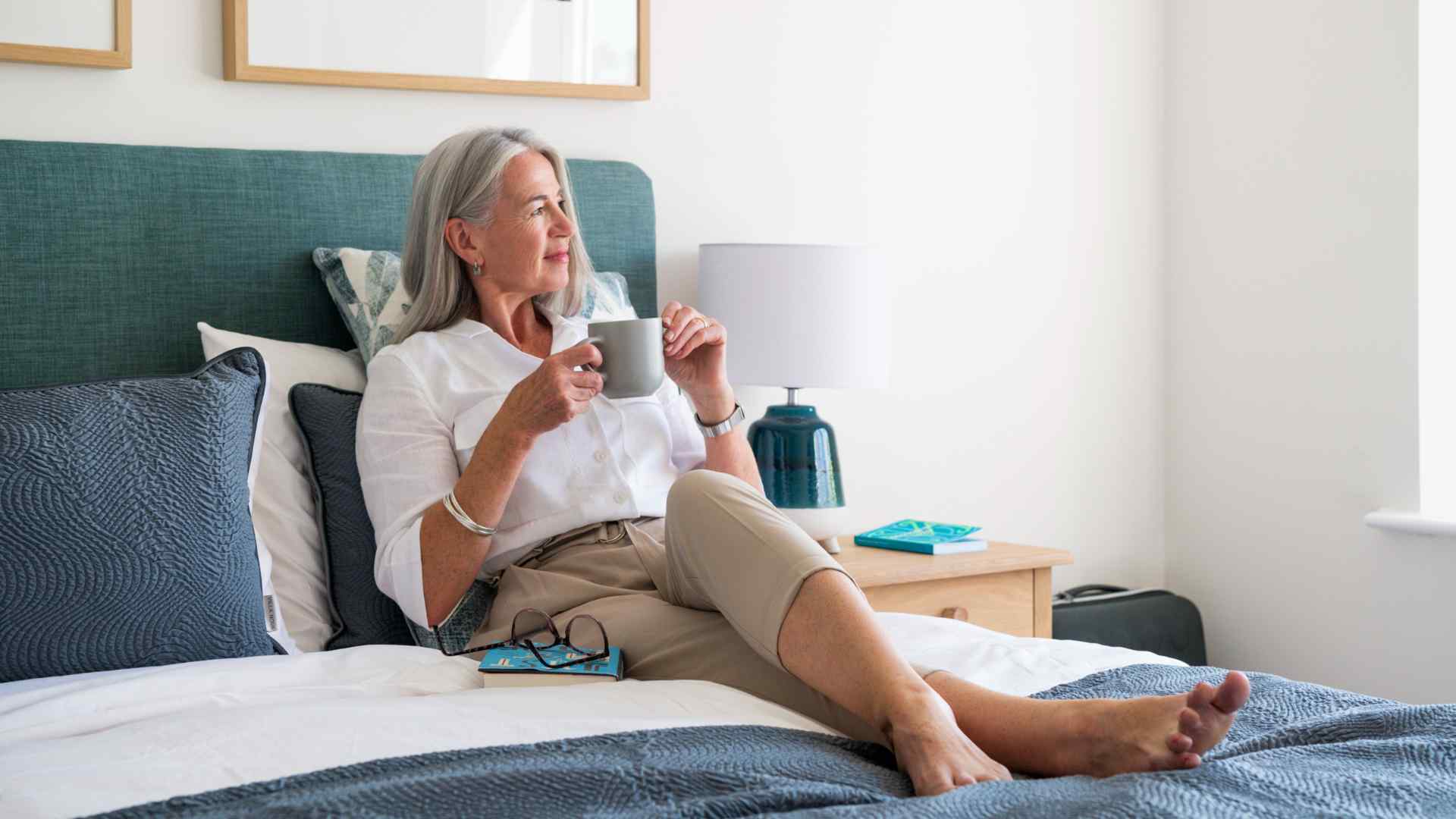 A lady lying in her bed with a cup of tea