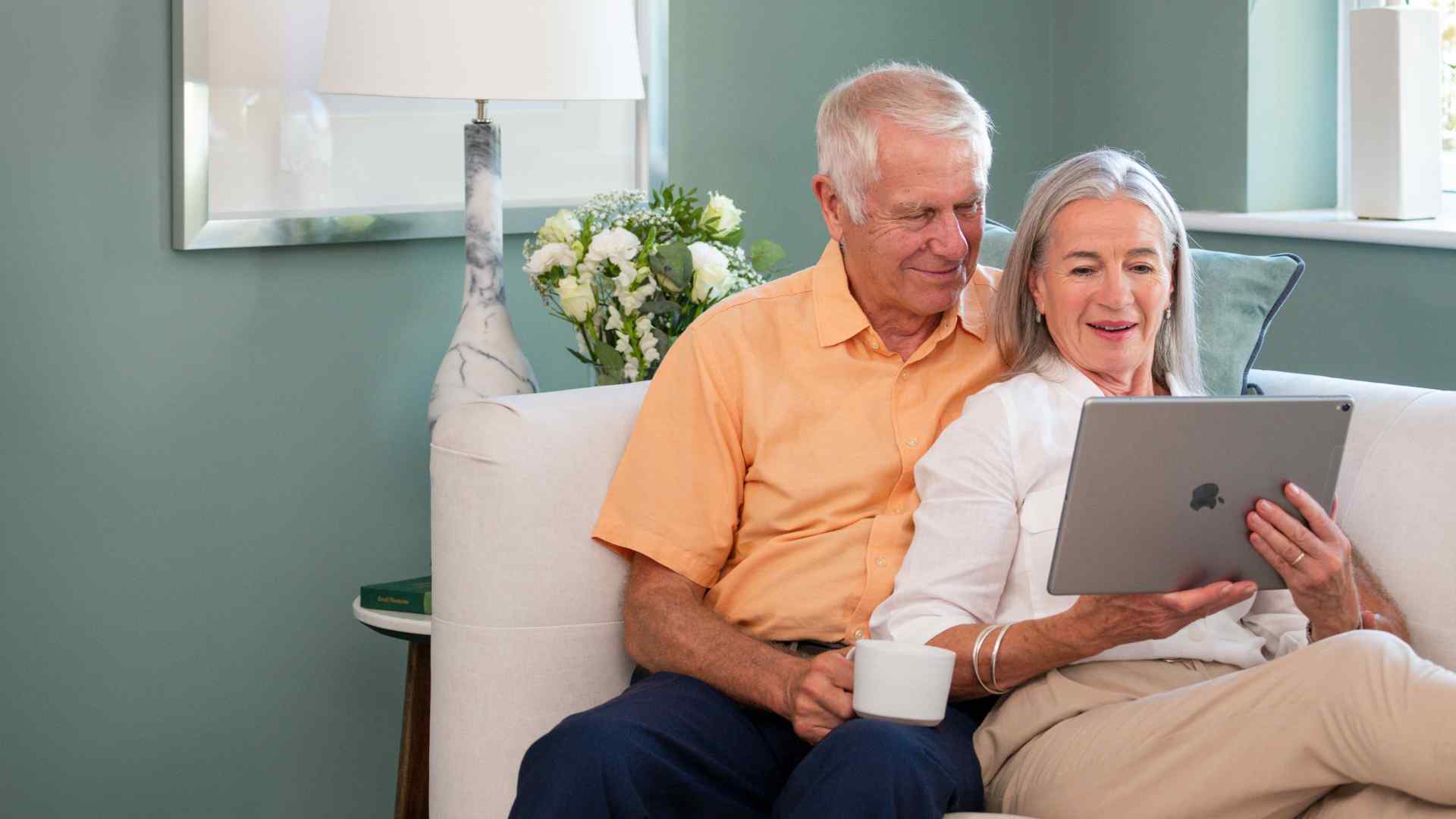 Man and woman lying on a sofa looking at a laptop.