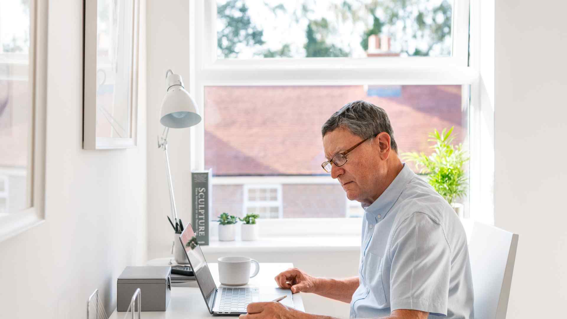 A man wearing a shirt working in his study.