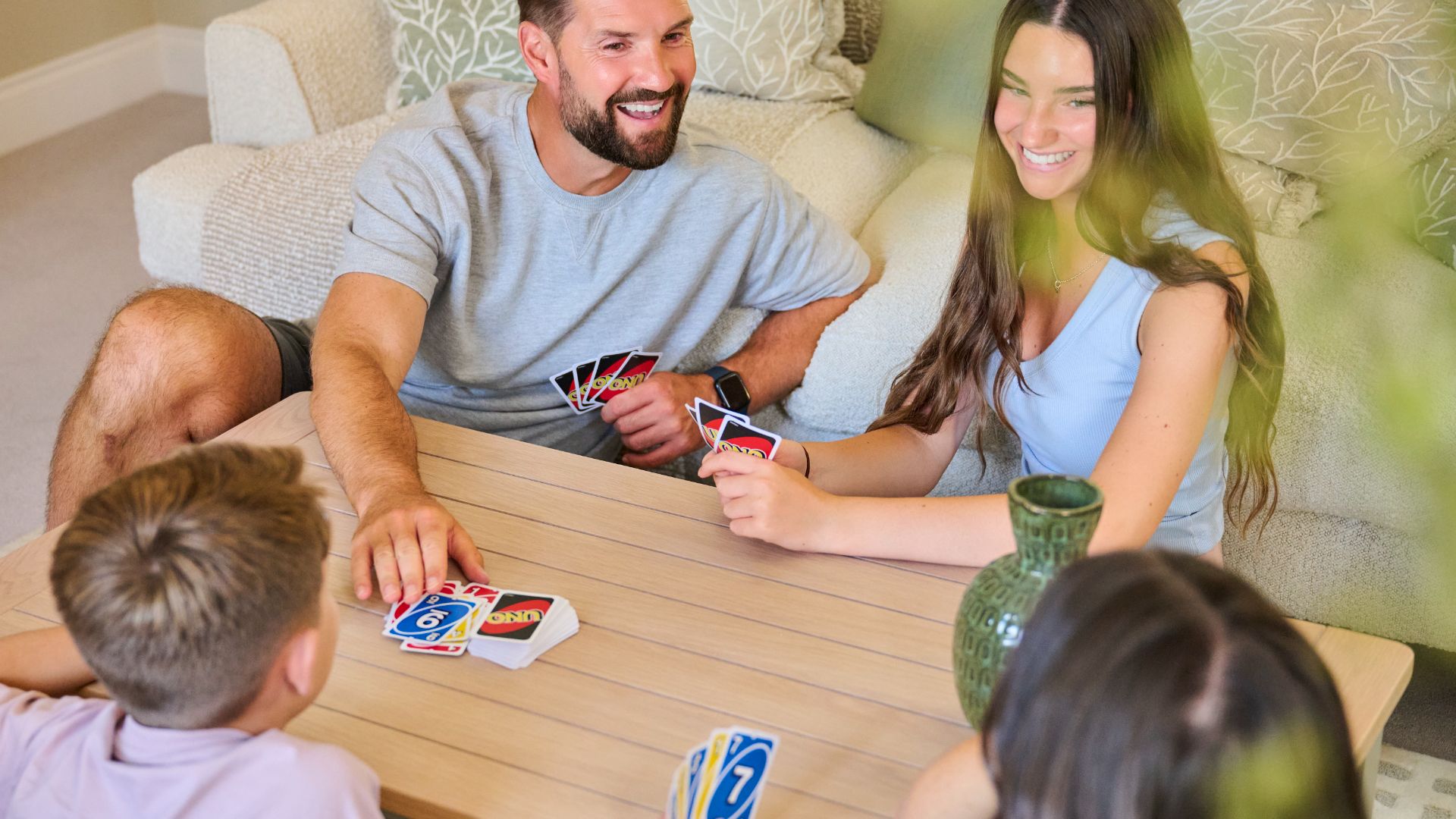 Family members smiling while playing a card game together in a living room