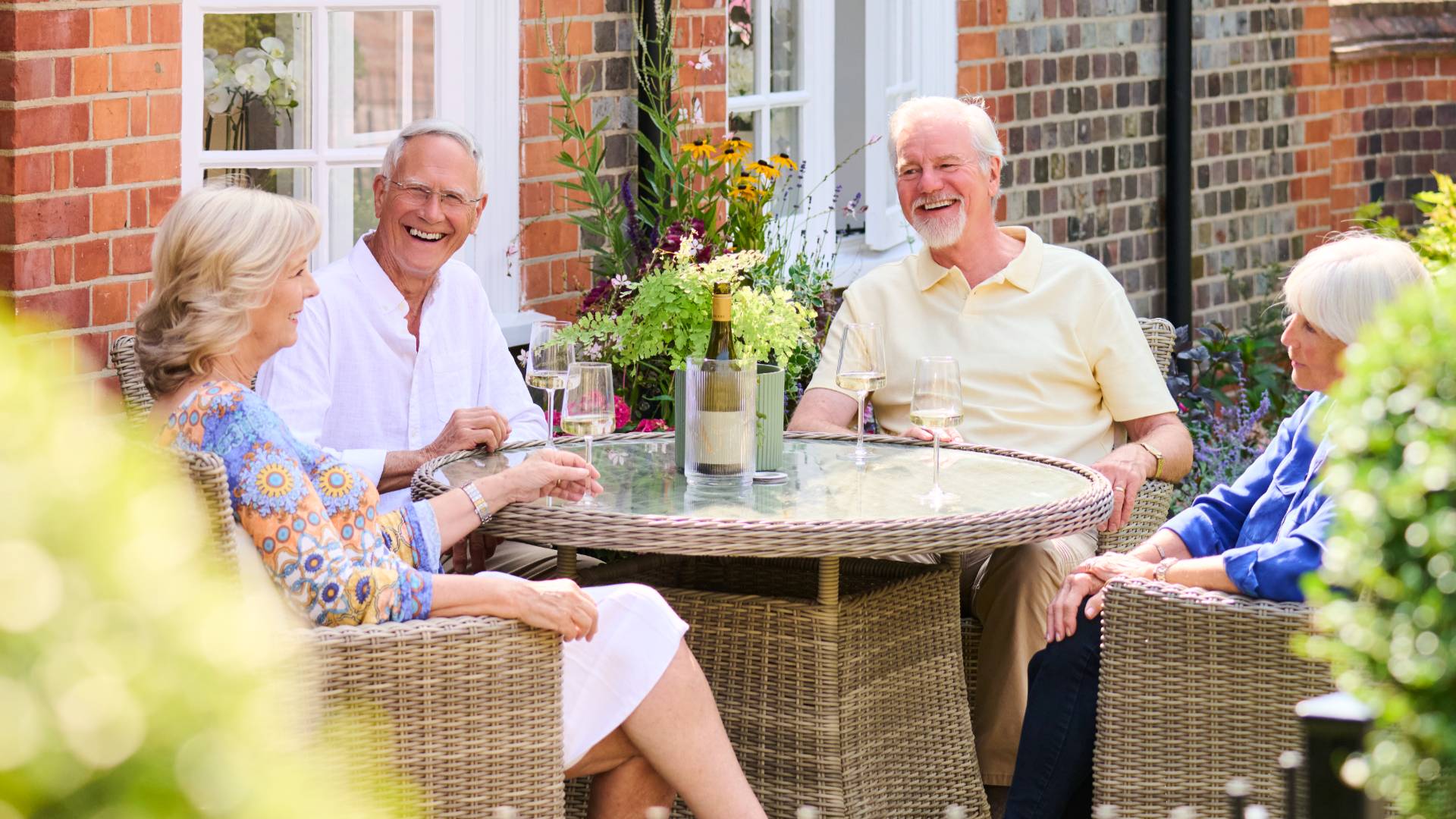 Four adults enjoying conversation and laughter together on a garden terrace