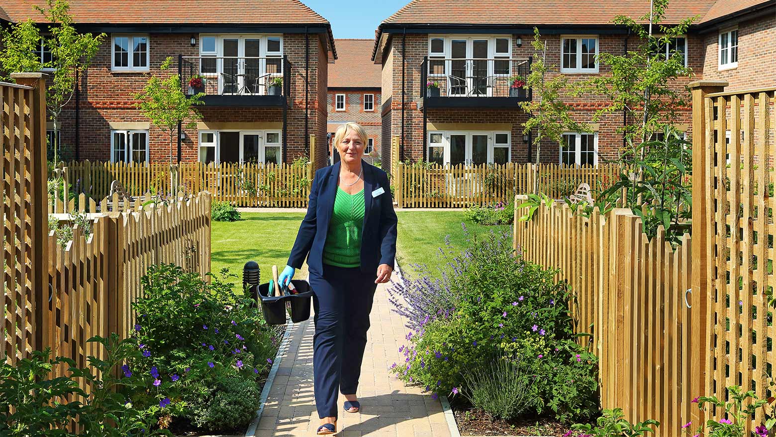 A Beechcroft Developments Estate Manager walking through the grounds of a development with cleaning supplies.