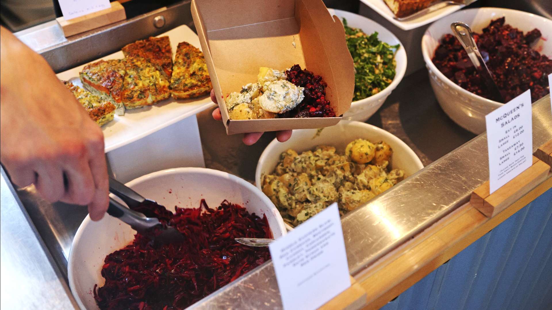 A lady being served coffee by a waitress in a black in Burford. 