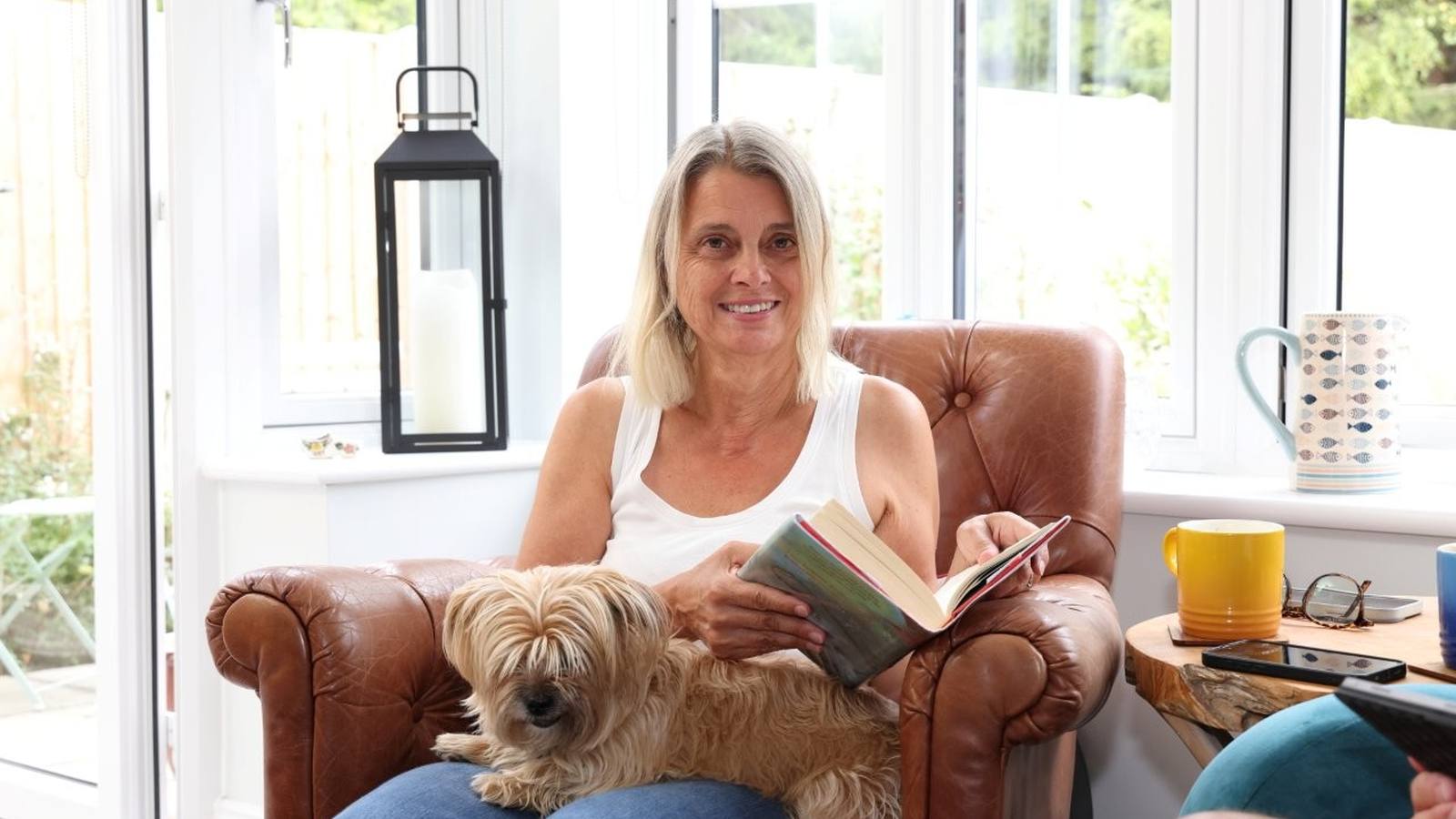 Cathy White relaxing with her dog in the sunroom at Manor Gardens, Shiplake