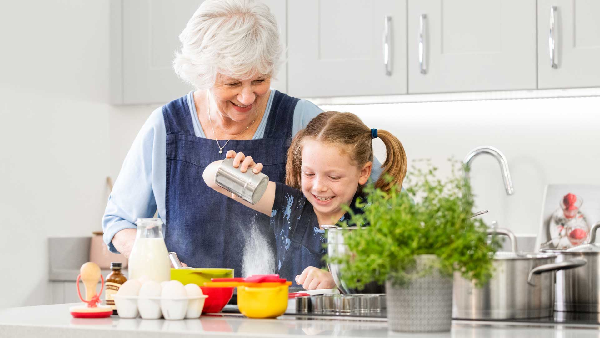 A grandmother preparing food with her granddaughter