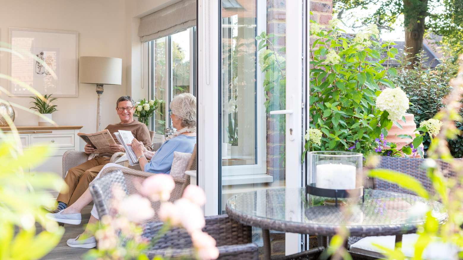 An older couple sat in their sunroom with the back doors open.