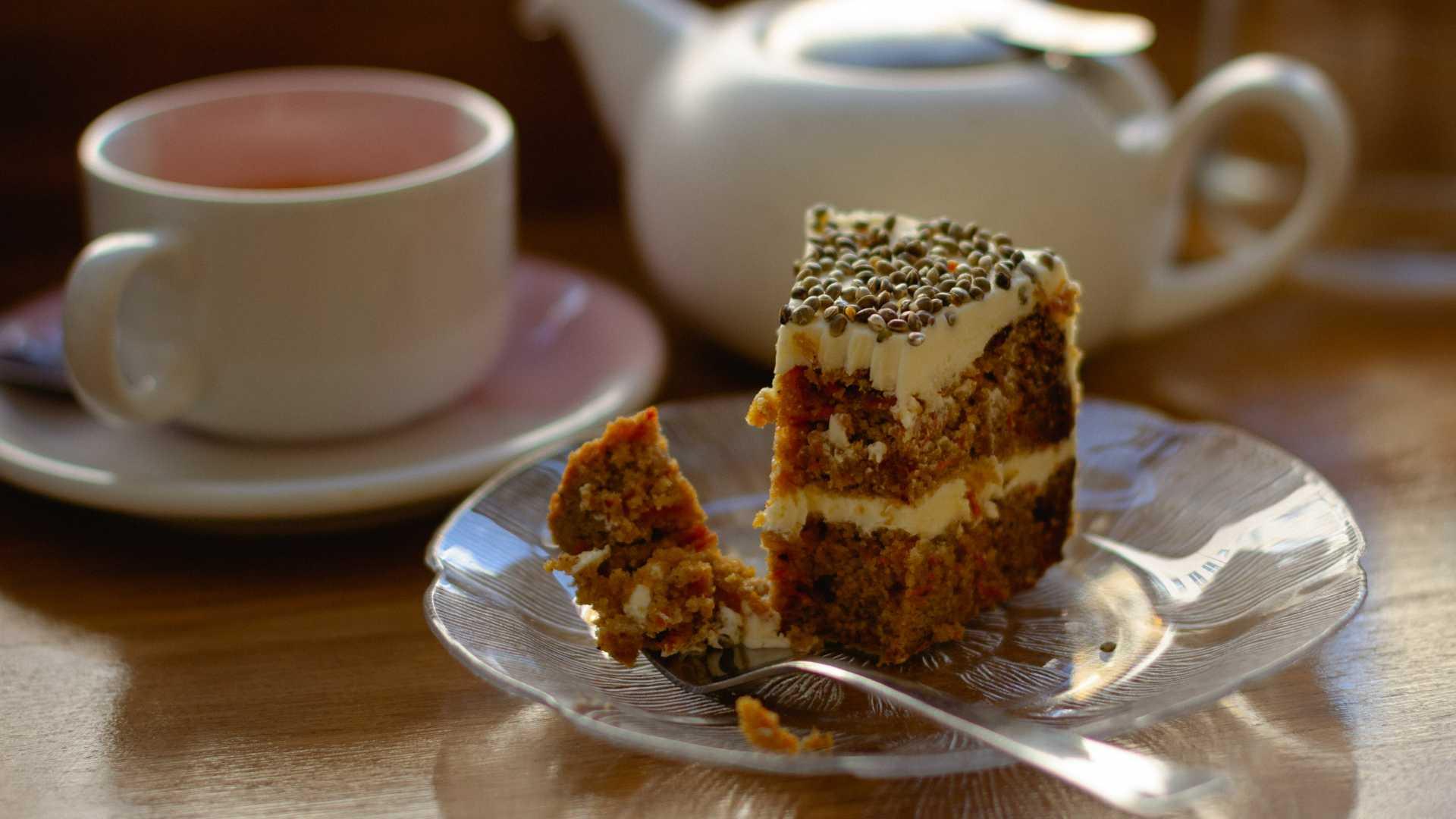 A slice of carrot cake with a cup of tea