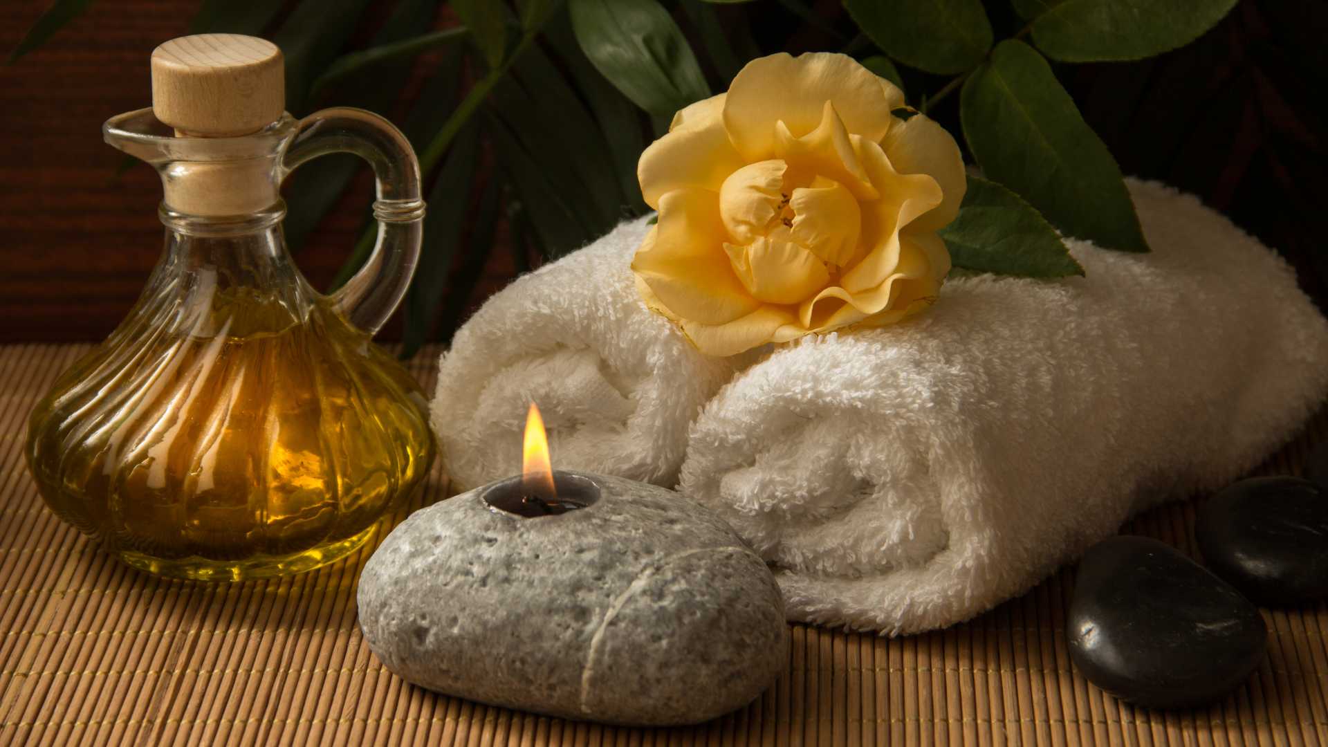 A photo of some spa oils, towels and a candle.