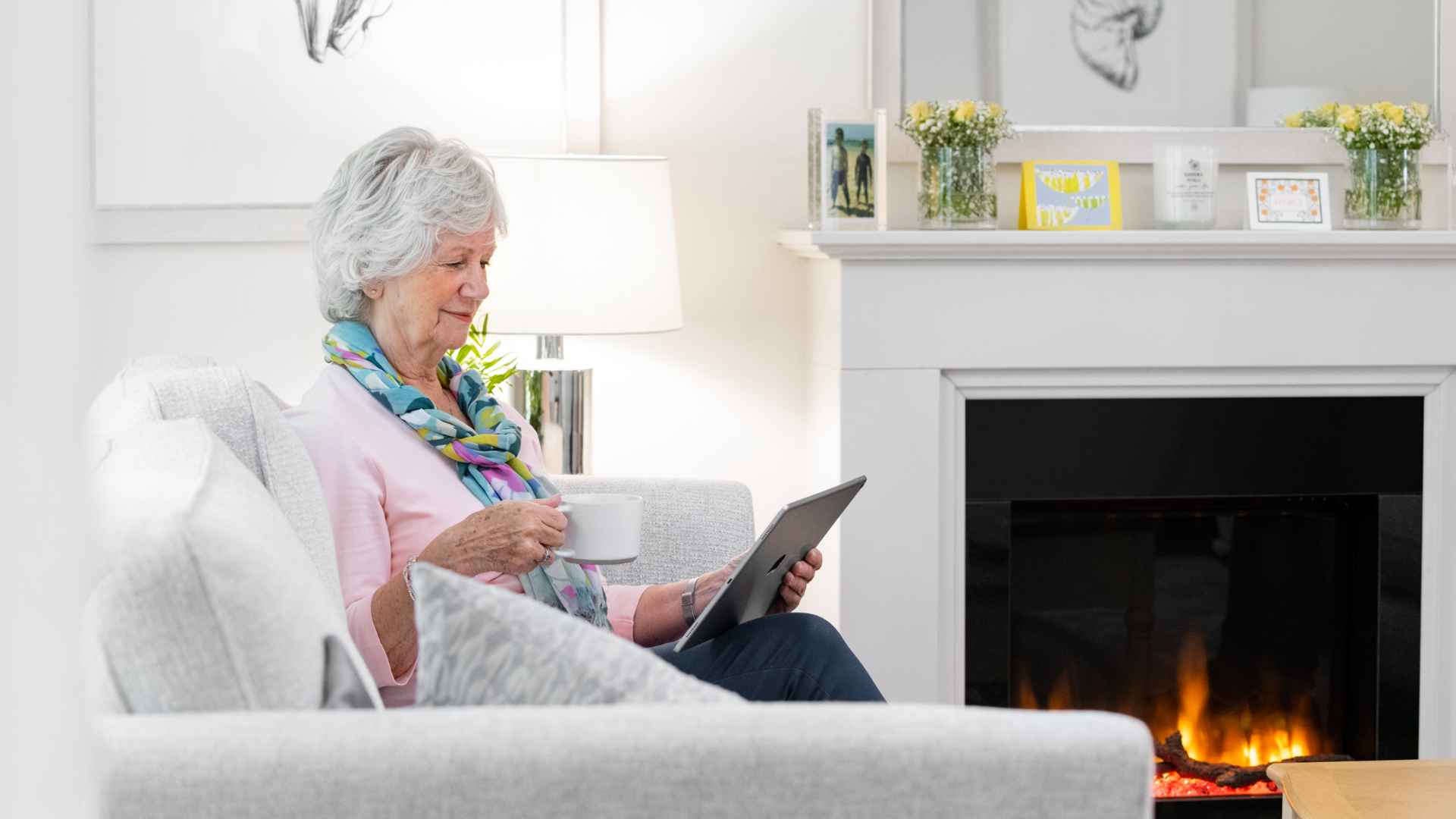 A lady using her iPad with a fire lit
