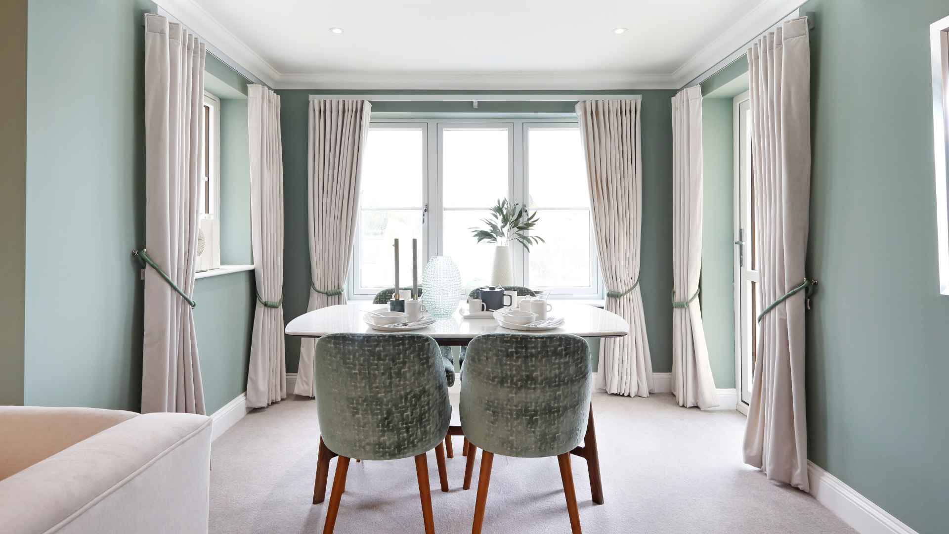 A dining table surrounded by windows and curtains