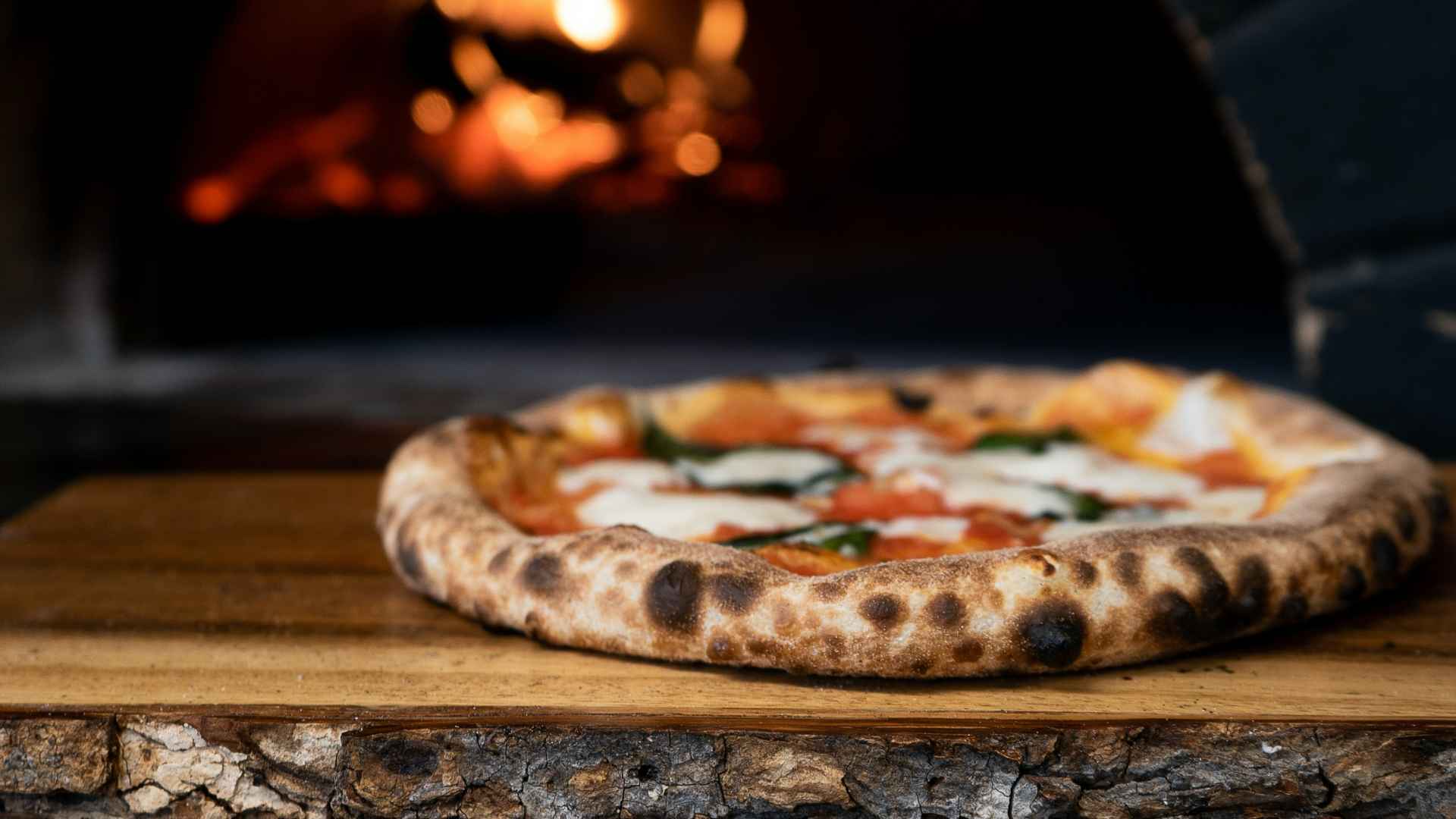 A wood fired pizza next to a pizza oven