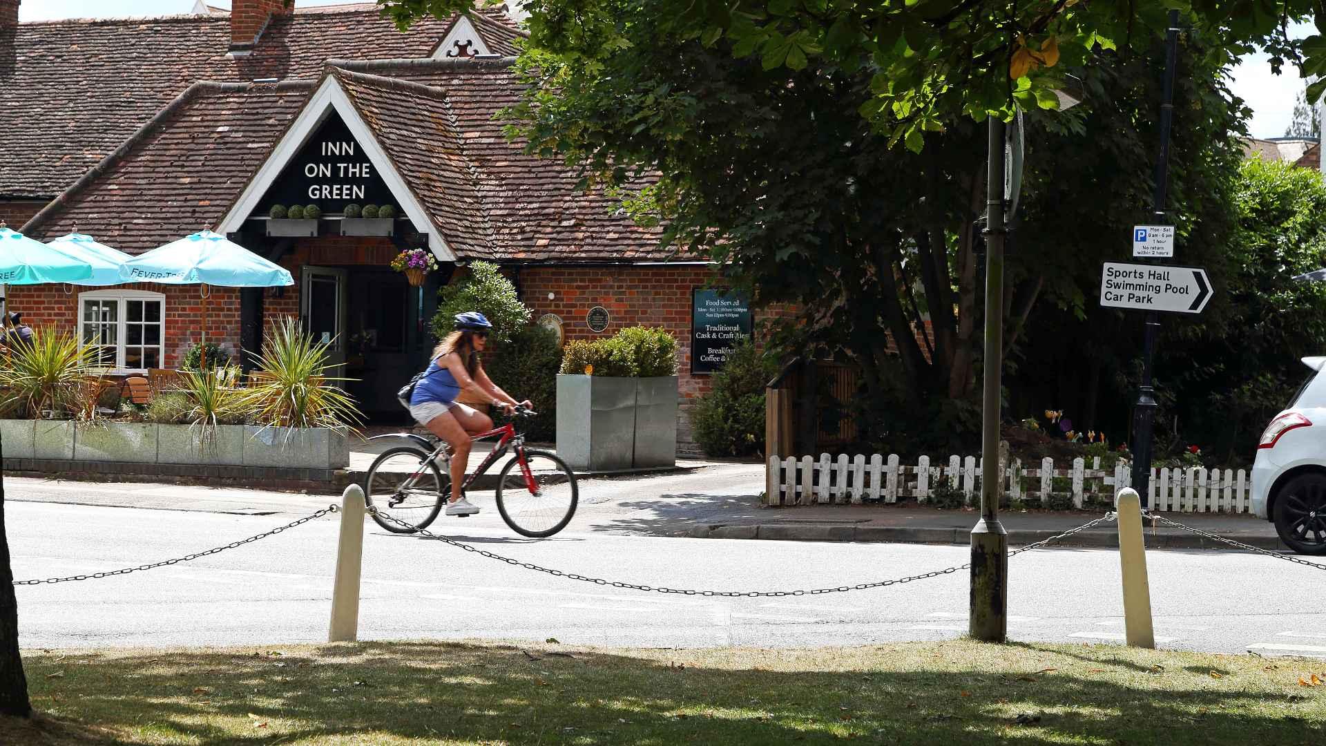 A cyclist cycling past the Inn On The Green in Harpenden