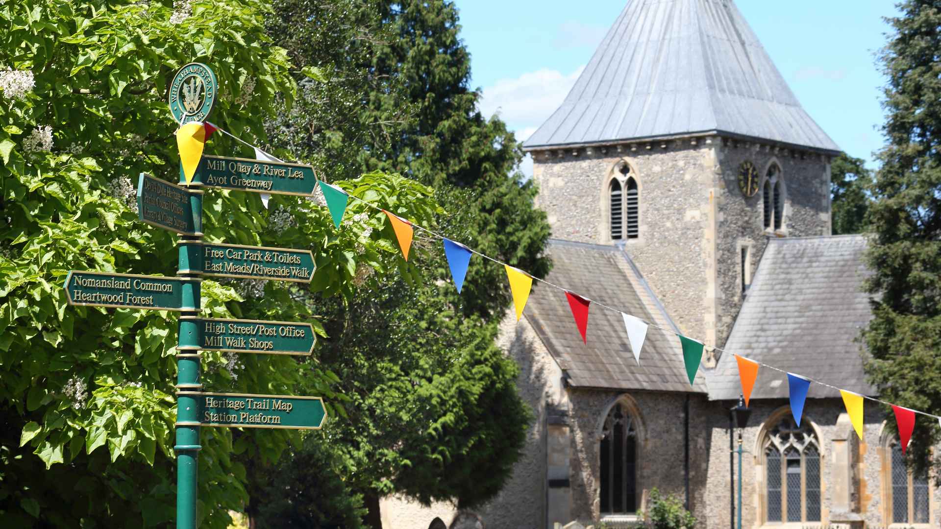 A sign post with bunting on it in a small village