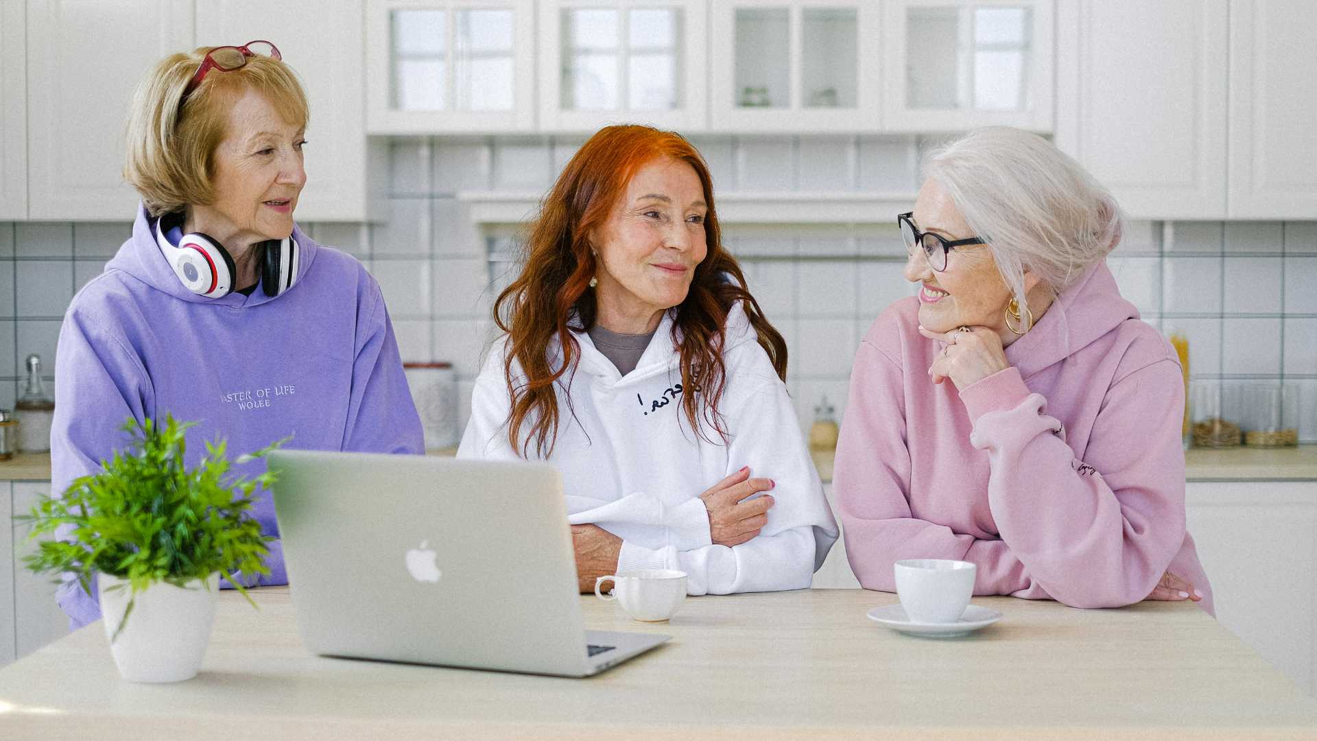 Three ladies with a laptop in a kitchen.