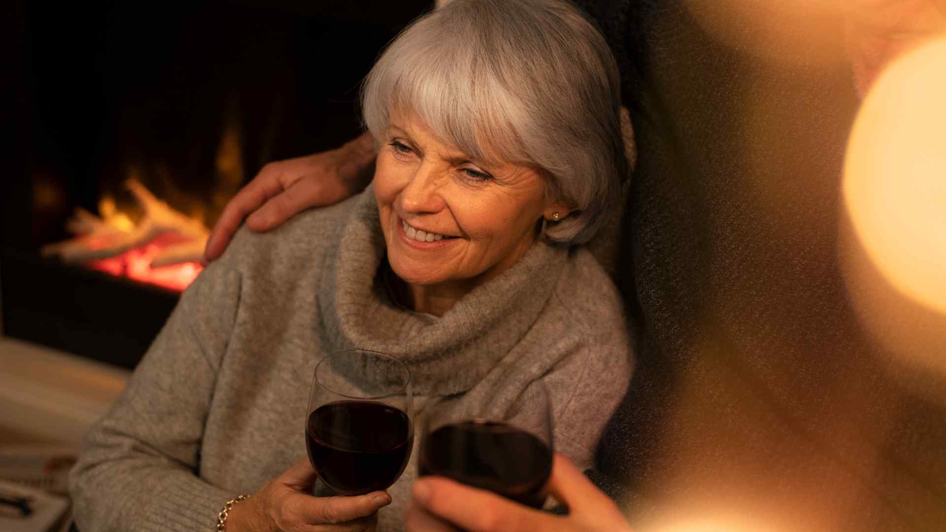 An older lady drinking red wine