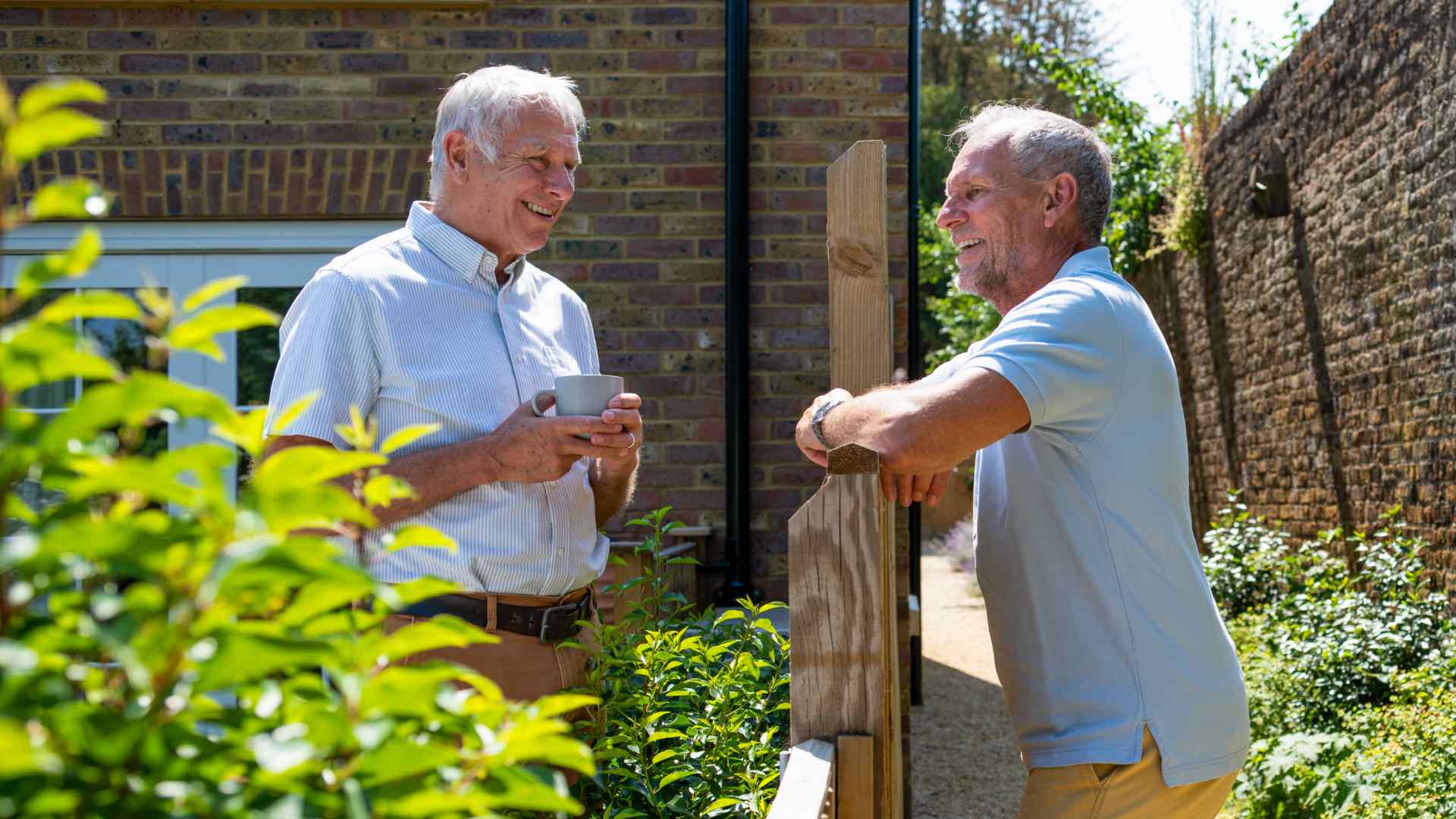 Two men talking to one another over a garden fence