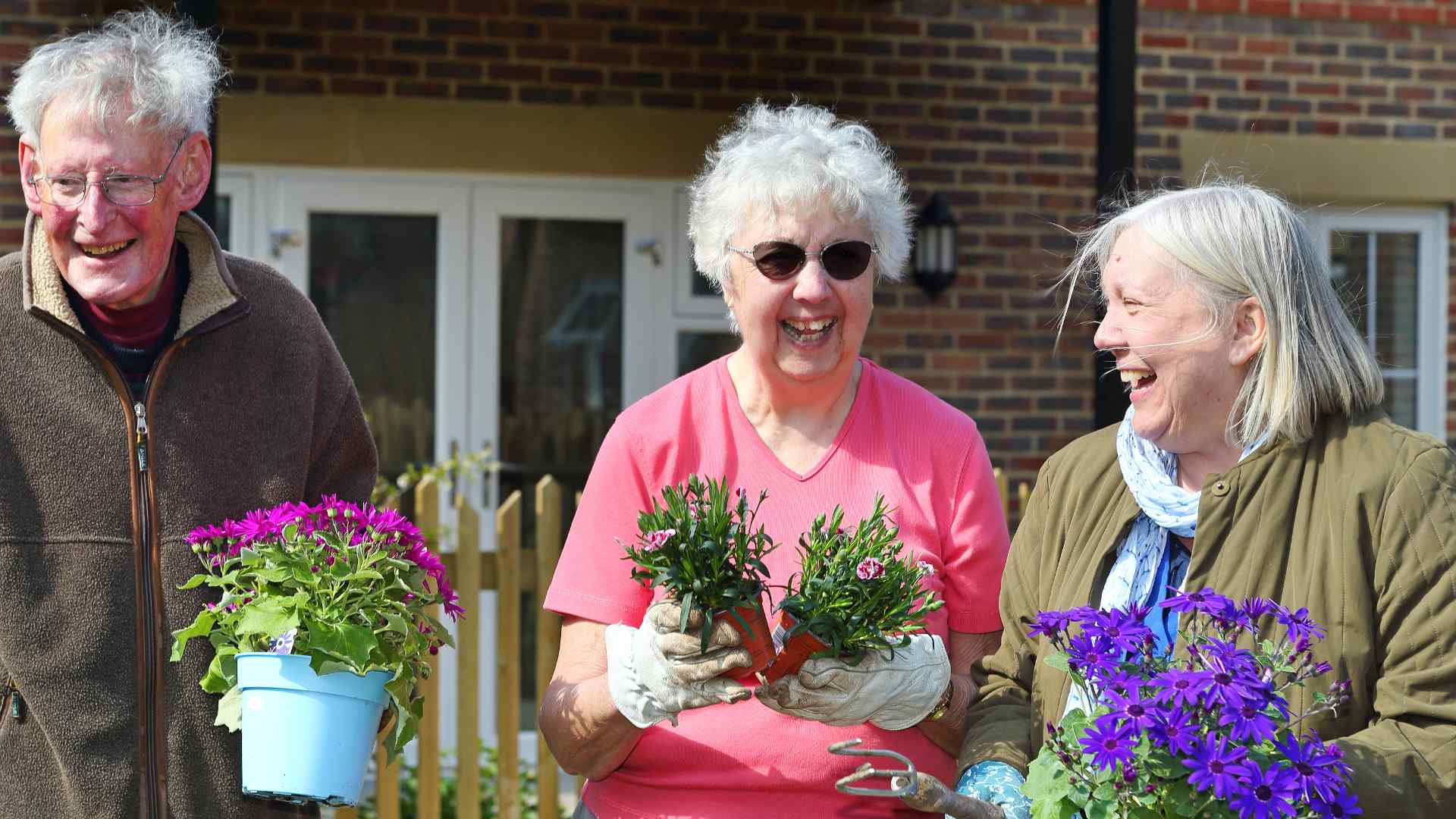 Three people holding potted plants