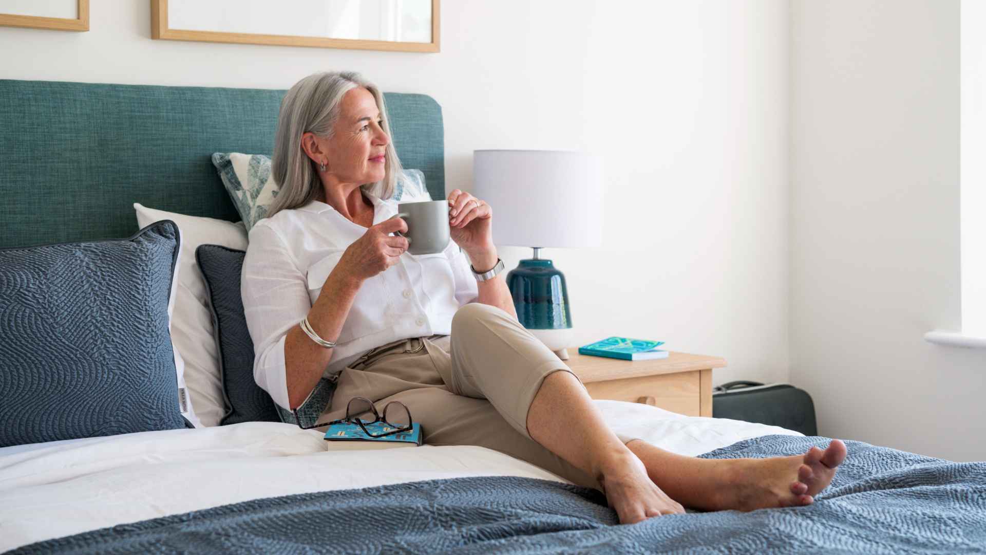 A photo of an older lady reading a newspaper in her drawing room