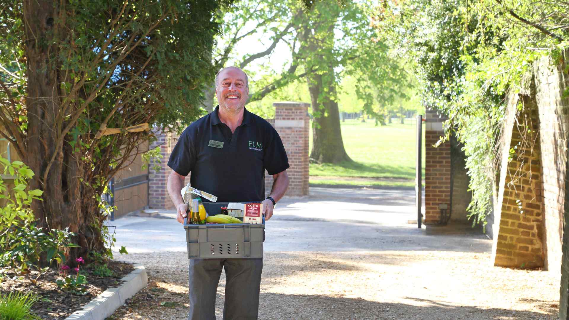 An Estate Manager carrying a box of groceries for a resident