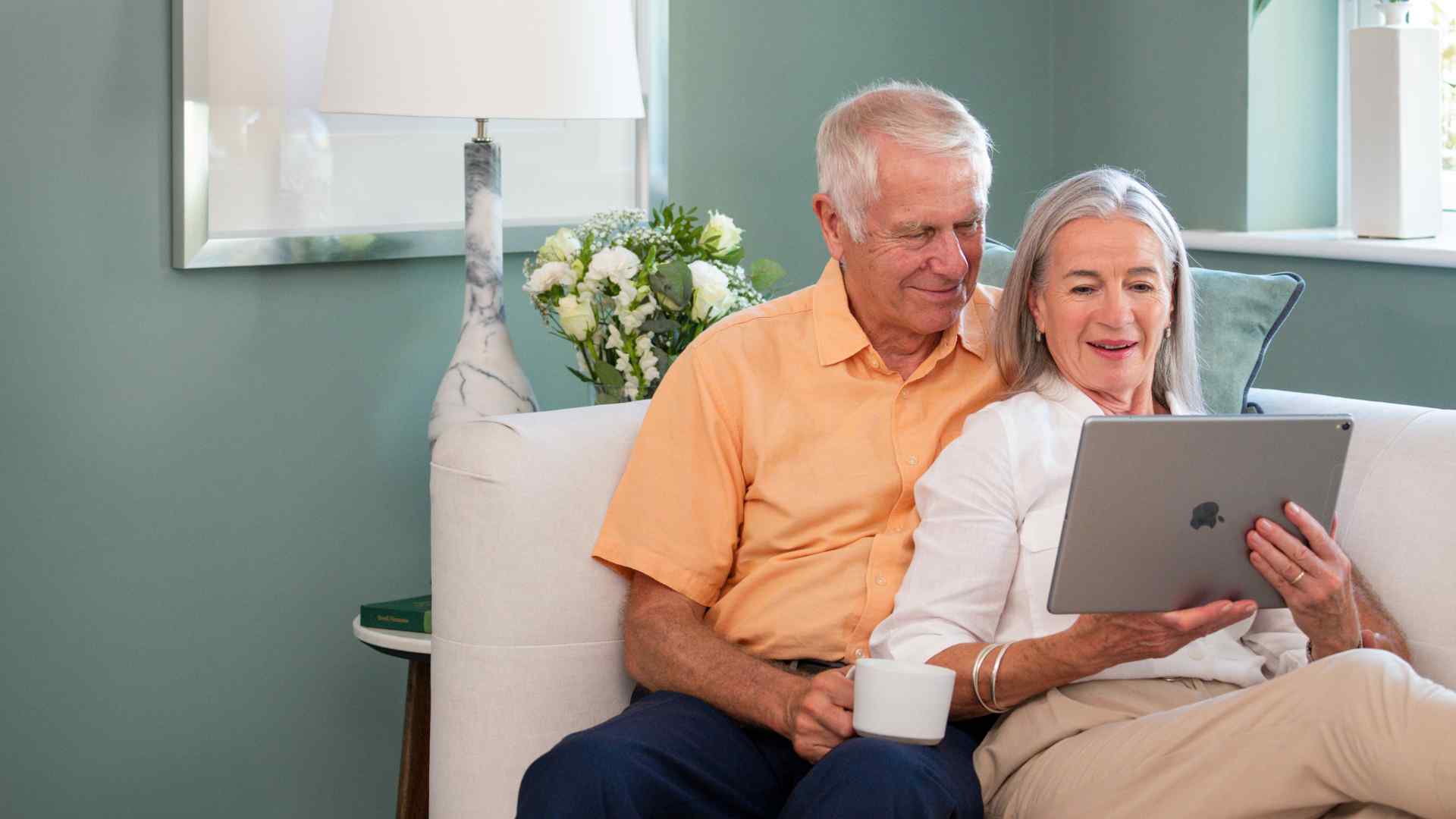 A couple using an iPad while sat on a sofa