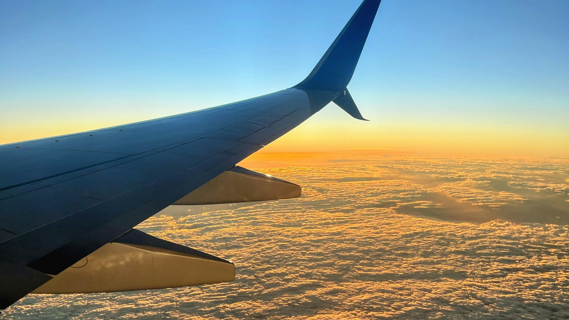 Airplane wing above the clouds at sunset, representing the freedom to travel in retirement