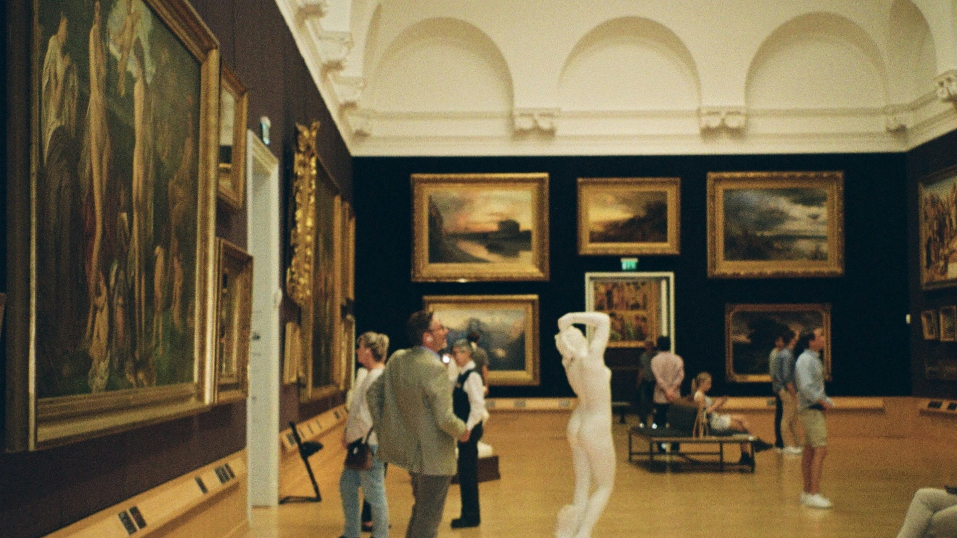 Visitors exploring paintings in a museum gallery on a cultural holiday